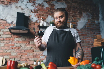 Surprised man with knife and pepper preparing food at kitchen