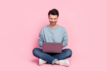 Full length profile photo of attractive young man sit floor work remotely laptop wear stylish blue outfit isolated on pink color background