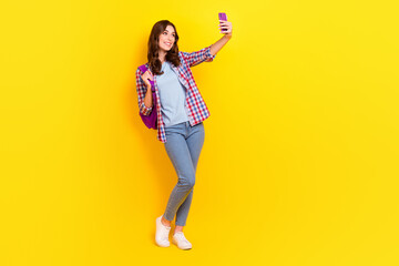 Fototapeta na wymiar Full body length photo of young adorable cute woman hold phone and new backpack after college video call parents isolated on yellow color background