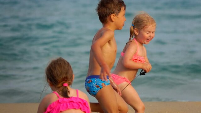 Cute little girl and boy are running along the seashore 