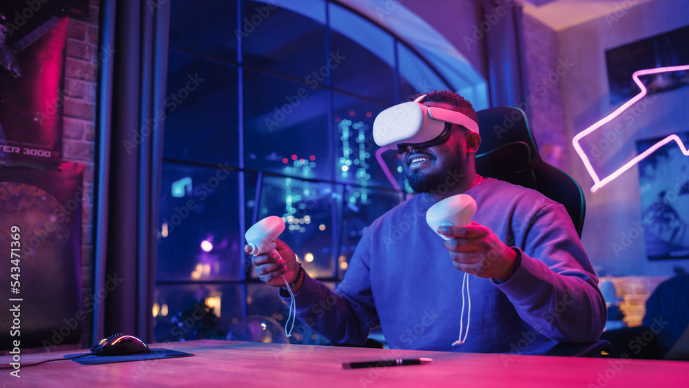 Poster stylish man using virtual reality headset with controllers at home in loft apartment. young african 