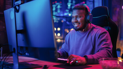 Gaming at Home: Portrait of a Happy African American Gamer Playing a Round in Online Video Game on Computer. Professional Stylish Male Player Enjoying Online Multiplayer PvP Tournament. Static Shot. © Gorodenkoff