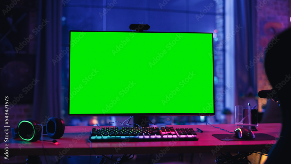 Poster gaming at home: empty gamer station with player's personal computer with green screen chroma key dis