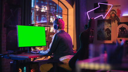 Attractive Female Gamer Playing Online Video Game with a Mock Up Green Screen on Her Powerful Computer. Room and PC have Colorful Neon Led Lights. Cozy Evening at Home in Modern Apartment.