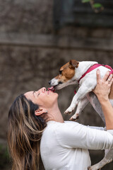 Woman holding Jack Russell dog liking her face 