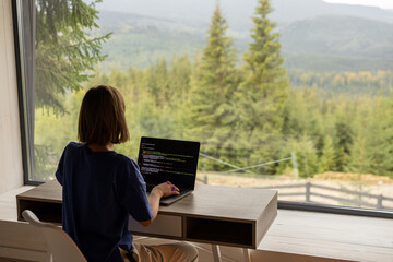Woman works on laptop remotely in house on nature