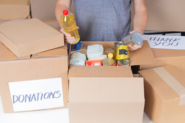 Man hands holding cardboard box with grocery products. Volunteer collecting food into donation box. Donation, charity, food bank, help for low income, poor families, migrants, refugee, homeless people