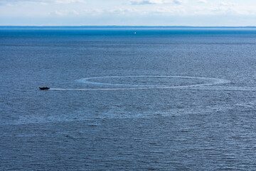 RIB boat circling in a loop in the summer waters outside of Kullaberg, Skåne, Sweden. Inflatable boat going fast in the calm baltic sea, turning around in a circle before going forward again
