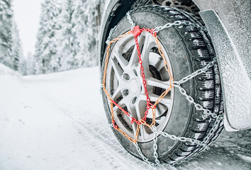 Snow chains on tire of car on snowy road in winter