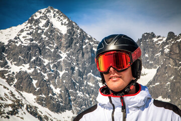 Fototapeta na wymiar Male skier with ski goggles and helmet and snowy peak at background