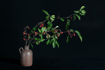 Branches of red berries in brown vase.