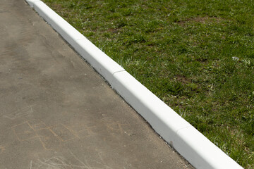 Painted curb. White curb on road. Landscaping in city.