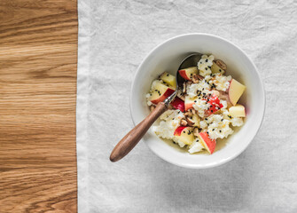 Delicious breakfast - cottage cheese with apple, honey, nuts on a wooden background, top view