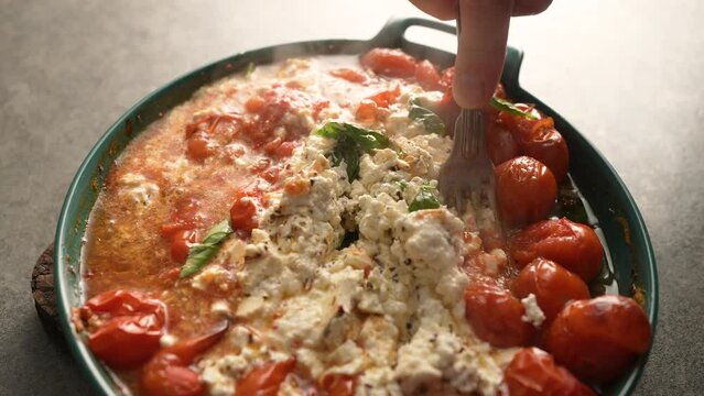 Cooking delicious homemade feta cheese pasta sauce with cherry tomatoes and basil. Drizzled with olive oil in a baking dish with a feta cheese in the middle and sprinkled with freshly ground pepper.