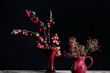 Branches of ornamental apple and red berries in red vases.