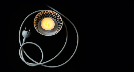 Burning candle in aluminium container with polkadot bowl and electric cable with a plug