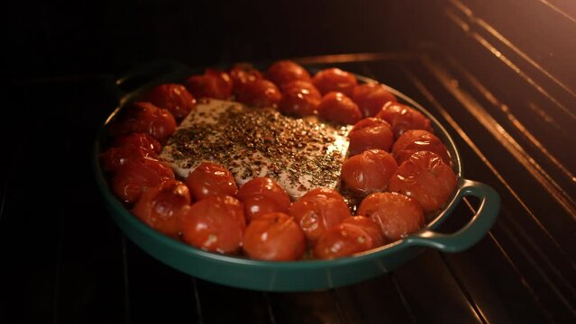 Cooking delicious homemade feta cheese pasta sauce with cherry tomatoes in a baking dish baked in the oven