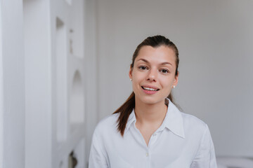 Close up portrait of pretty businesswoman with ponytail toothy smiling looking at camera. Open...