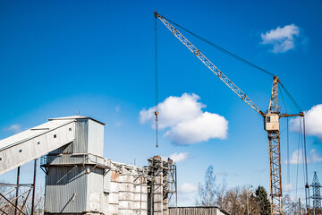 Tower crane against blue sky in old concrete factory.