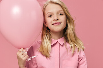 Obraz na płótnie Canvas little girl, blonde, stands smiling happily with a pink balloon in her hands