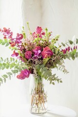 Vertical shot of a beautiful bouquet of mild flowers in a glass vase