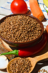 Buckwheat in a bowl, red pepper, carrots and onions on the board.