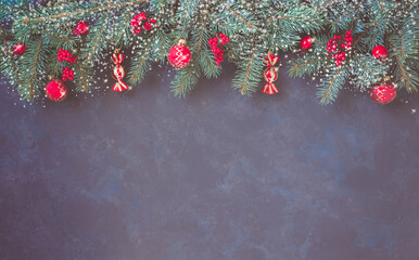 Christmas dark lilac grunge horizontal background, top view. Fir twigs, red golden berries, baubles. Winter holidays, New Year decoration, pine tree branches, snow covered cones, copy space.