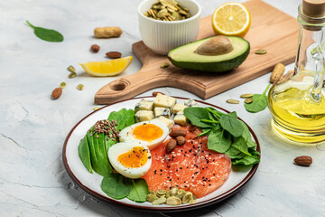 Keto diet food, salmon, avocado, cheese, egg, spinach and nuts. Ketogenic low carbs diet concept. Ingredients for healthy foods selection, place for text, top view