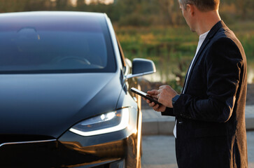 Businessman controls a self-driving electric car using mobile application. Autonomous autopilot...