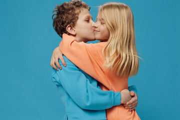 beautiful, cute children, brother and sister stand on a blue background hugging each other. Themes of relationships and friendship between children