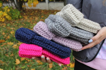 Fototapeta na wymiar Hats crocheted knitted in the hands of a girlon the street. Product listing for sale. Urban style. Fashion. Autumn