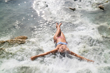 Girl doing a natural hydromassage under a waterfall at the free spa of Saturnia