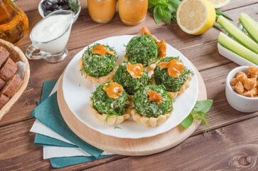 Tartlets stuffed with beef, champignons and potatoes with greens on a white plate on a dark wooden background