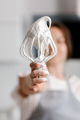 Woman confectioner prepares meringue in the kitchen. Whisk with meringue. High quality photo