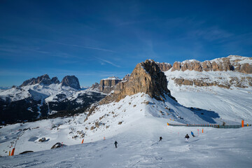View of a ski resort piste with people skiing in Dolomites in Italy. Ski area Belvedere. Canazei, Italy