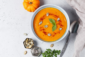 Cream soup of baked pumpkin and carrots with cream and pumpkin seeds with herbs on a gray background. Vegan food.Copy space