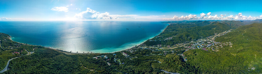 aerial panorama view of the Black Sea coast of the forested mountains of the Caucasus near the resort village of Shepsi on a sunny summer day