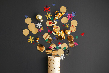 Merry Christmas and Happy New Year! Modern colorful confetti popping from golden wrapping paper on...