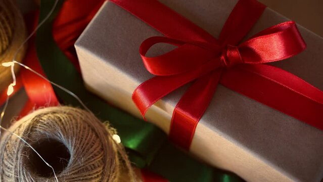 Cozy Christmas gift craft paper box with red ribbon bow. New year eve holiday composition with present handmade box. Christmas eve preparation. Family time, cozy home
