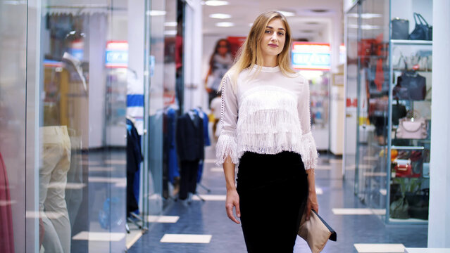 Sexy girl, tall, beautiful blond woman walking down the hall of shopping center, along the windows of shops and stylish boutiques. Shopping in a stylish clothing stores. High quality photo
