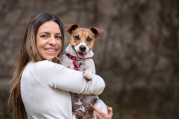 Woman holding Jack Russell dog posing for the camera at the park during the day