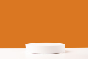 Empty white round podium stage on orange backdrop. Mockup scene for product presentation. Studio photography. Product showcase or display.