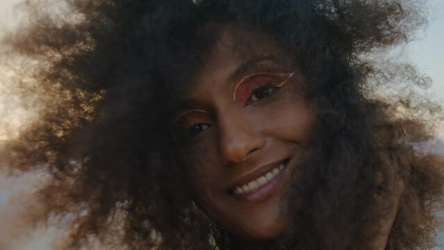 Curly girl smiling camera at gloomy nature close up. Portrait african woman.
