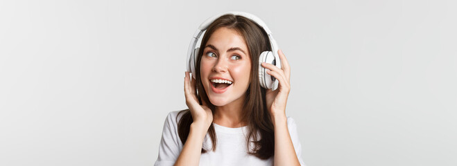 Close-up of beautiful happy girl smiling, enjoying listening music in wireless headphones