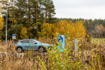 Electric car is charging at a charging station in a natural surrounding with autumn colors in Sweden
