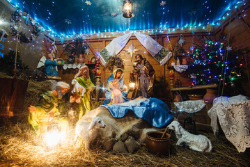 Christmas crib at a Cologne Christmas market. The scene where the Virgin Mary gave birth to Jesus and he lies in the cradle surrounded by people who have come to celebrate the Nativity of Christ - obrazy, fototapety, plakaty