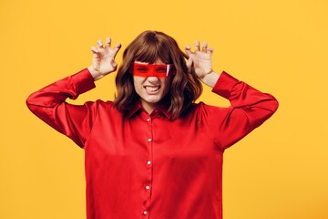a funny, funny, playful woman stands on a yellow background in a red shirt and fashionable glasses...