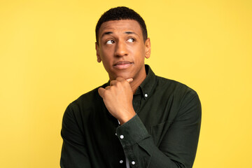 Portrait of thoughtful brunette man holding his chin and pondering idea