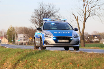 Samochód służbowy polskiej policji państwowej podczas akcji na drodze za miastem.  - obrazy, fototapety, plakaty
