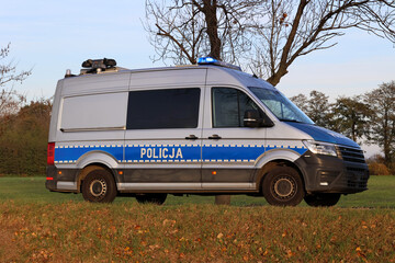 Samochód służbowy polskiej policji państwowej podczas akcji na drodze za miastem. 